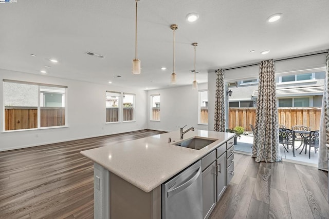 kitchen featuring decorative light fixtures, stainless steel dishwasher, a kitchen island with sink, dark hardwood / wood-style floors, and sink