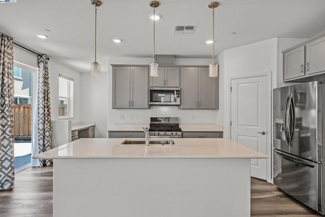 kitchen featuring pendant lighting, stainless steel appliances, a center island with sink, and dark hardwood / wood-style floors