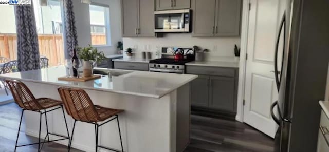 kitchen featuring gray cabinetry, stainless steel appliances, and a breakfast bar