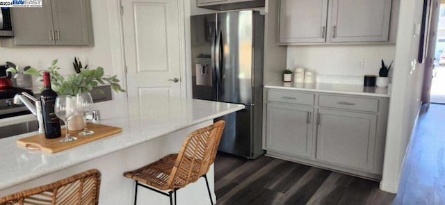 kitchen with gray cabinetry, dark hardwood / wood-style floors, and stainless steel fridge with ice dispenser