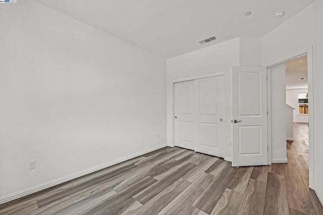 unfurnished bedroom with light wood-type flooring and a closet