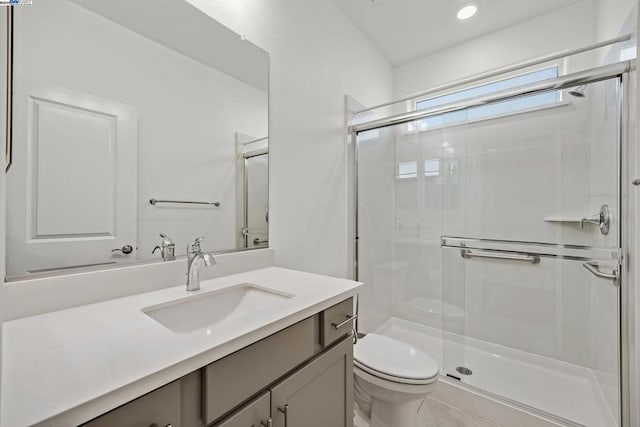 bathroom featuring a shower with door, vanity, and toilet