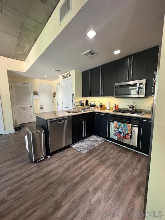 kitchen featuring appliances with stainless steel finishes, kitchen peninsula, sink, and dark wood-type flooring