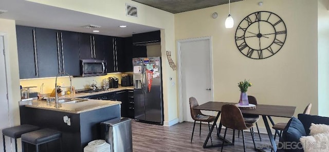 kitchen with sink, kitchen peninsula, decorative light fixtures, dark wood-type flooring, and appliances with stainless steel finishes