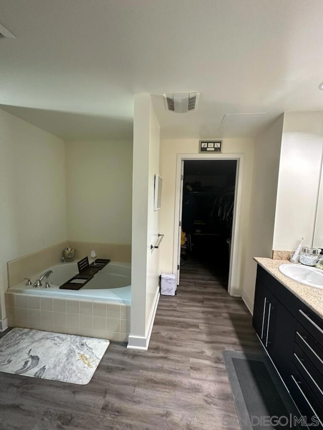 bathroom with tiled bath, vanity, and hardwood / wood-style flooring