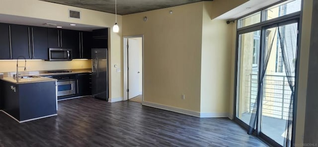 kitchen featuring pendant lighting, sink, kitchen peninsula, stainless steel appliances, and dark hardwood / wood-style flooring