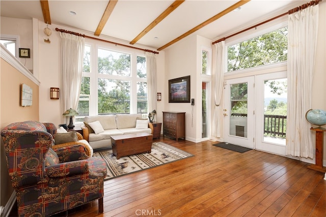 living room with a high ceiling, beam ceiling, and hardwood / wood-style flooring