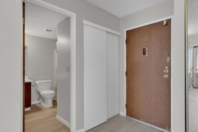 interior space featuring wood-type flooring, toilet, vanity, and a textured ceiling