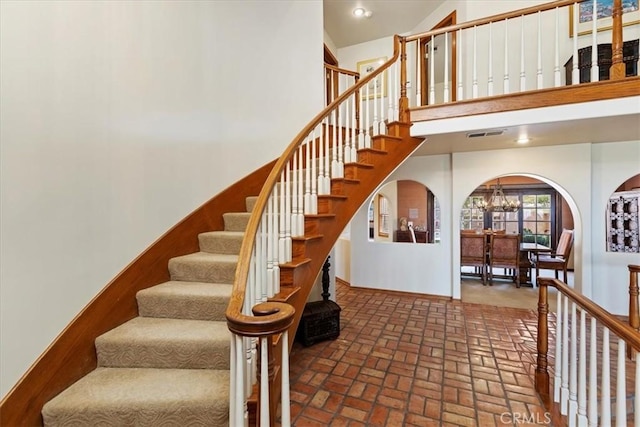 stairway with a chandelier and high vaulted ceiling