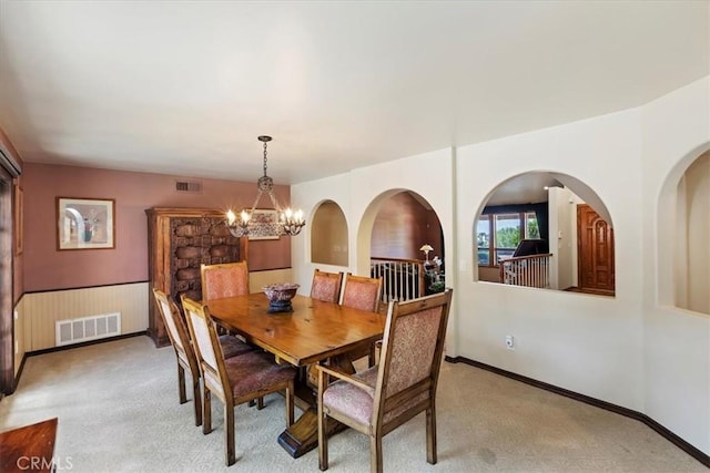 dining space with light carpet and an inviting chandelier