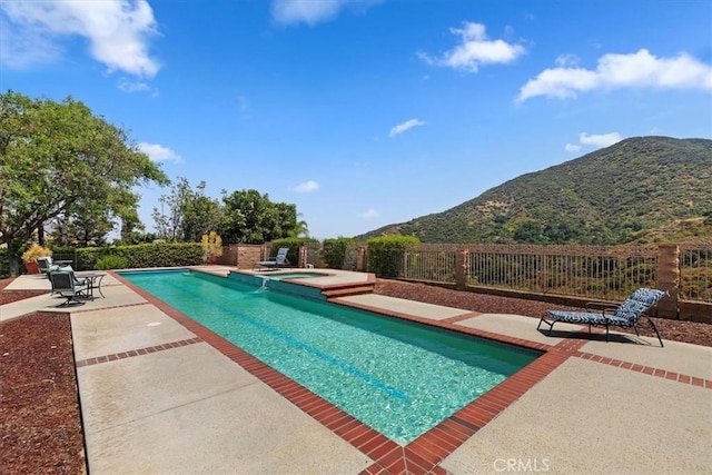 view of pool featuring a mountain view, an in ground hot tub, and a patio