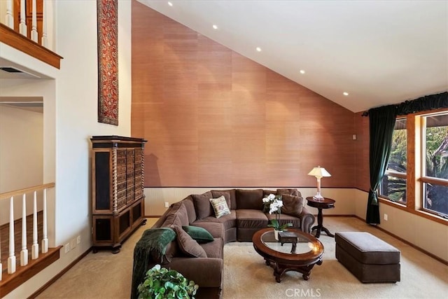 living room with carpet, wooden walls, and high vaulted ceiling