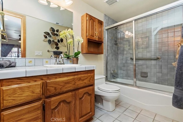 full bathroom with toilet, tile patterned flooring, vanity, and combined bath / shower with glass door