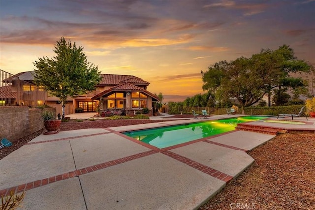 pool at dusk with a patio area