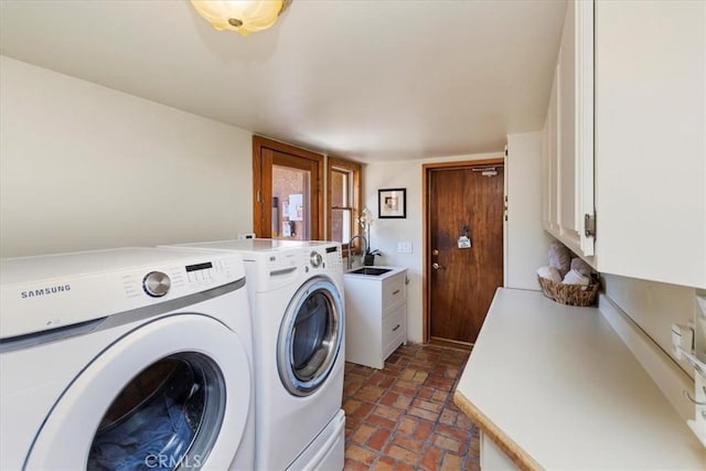 clothes washing area featuring washer and clothes dryer, cabinets, and sink