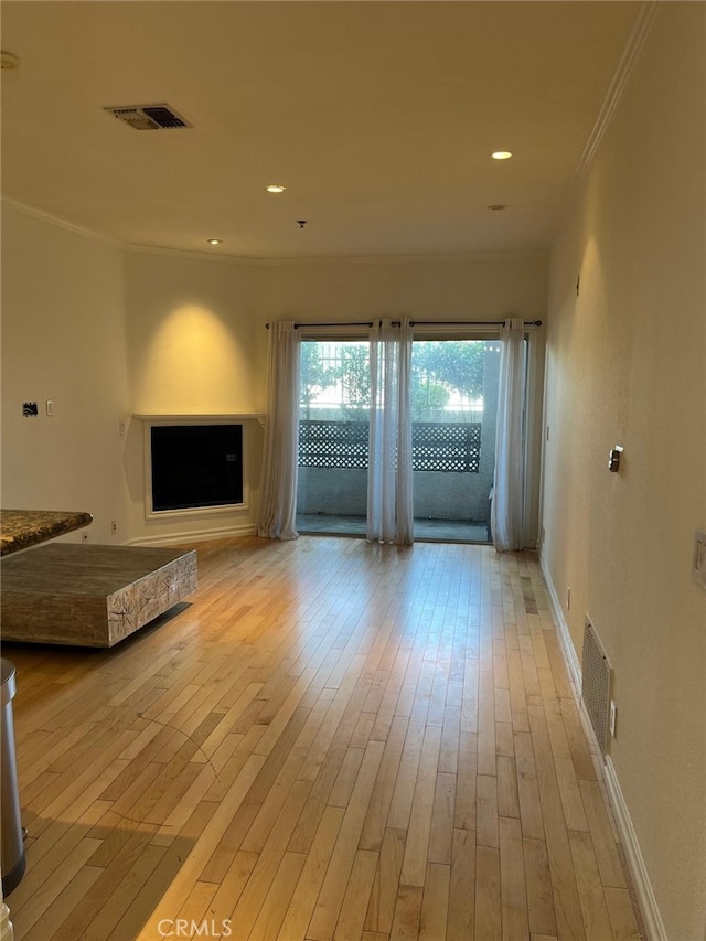 unfurnished living room featuring light hardwood / wood-style floors, ornamental molding, and a fireplace