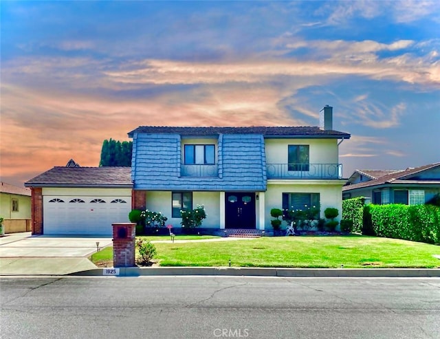 view of front of home with a yard, a garage, and a balcony