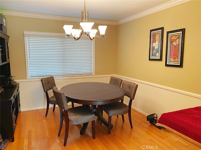 dining area featuring ornamental molding, a notable chandelier, and light hardwood / wood-style floors