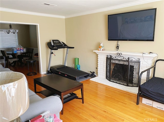 living room featuring ornamental molding, wood-type flooring, and a brick fireplace