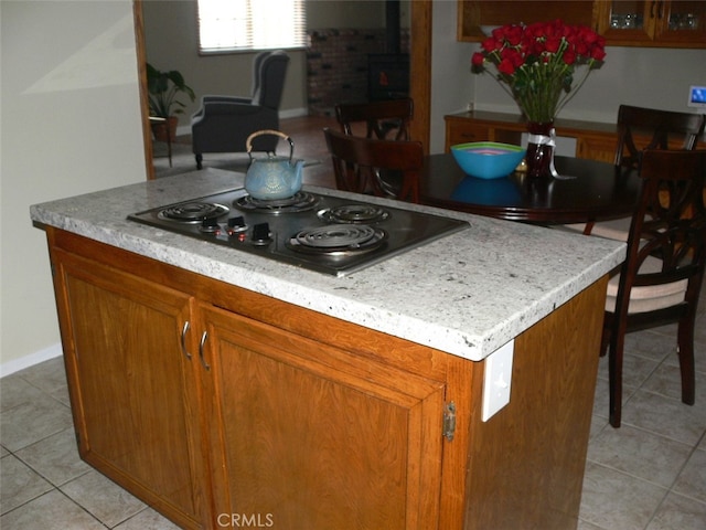 kitchen with black electric stovetop, a center island, and light tile patterned flooring