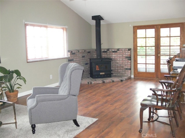 living room featuring vaulted ceiling, dark hardwood / wood-style floors, a wood stove, and french doors