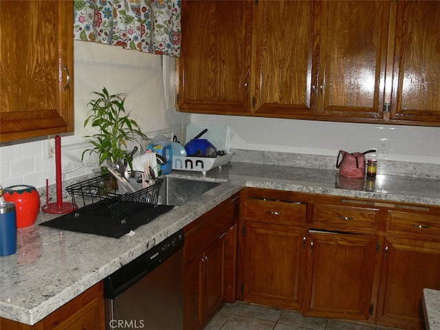 kitchen featuring backsplash, light tile patterned flooring, dishwasher, and light stone counters