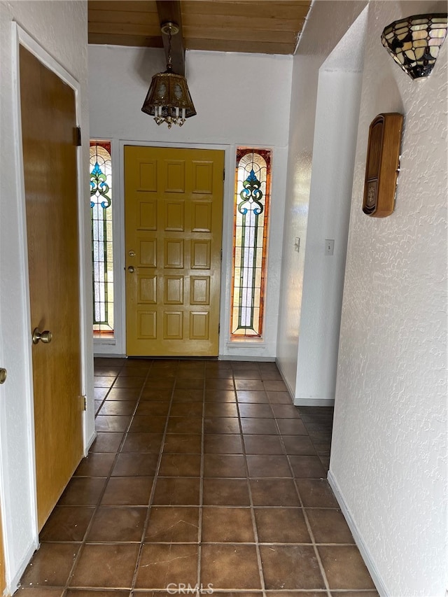 foyer entrance featuring dark tile patterned flooring and wood ceiling