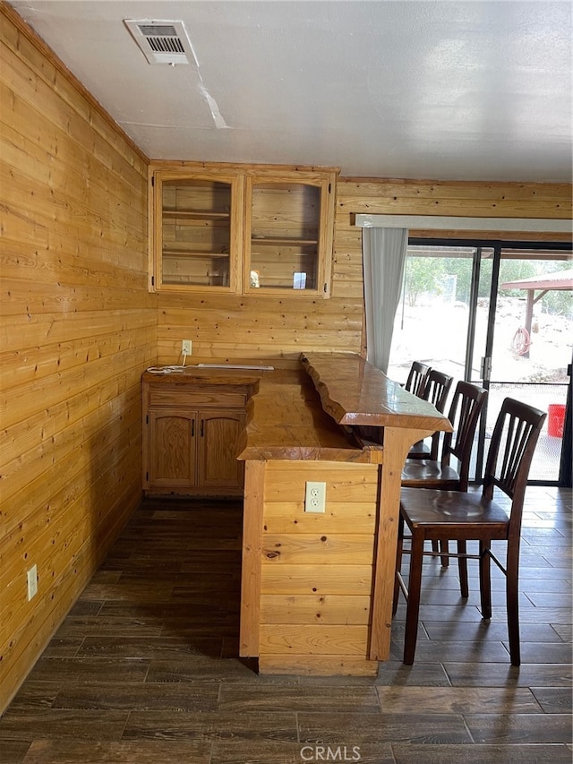 kitchen with a kitchen breakfast bar, wooden walls, and dark wood-type flooring