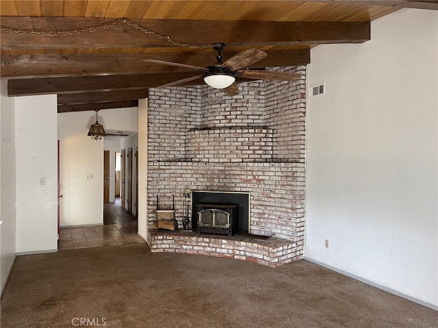 unfurnished living room featuring vaulted ceiling with beams, a wood stove, wooden ceiling, and dark carpet