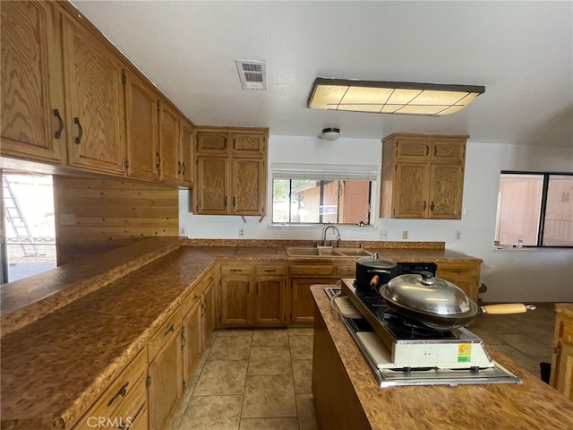 kitchen with sink, light tile patterned flooring, and wooden walls