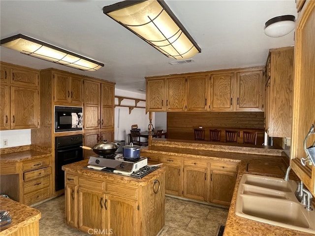 kitchen with sink, black appliances, and a center island