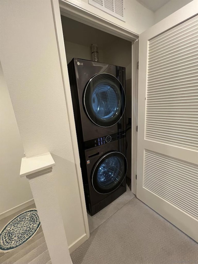 laundry room featuring stacked washer and clothes dryer and light colored carpet