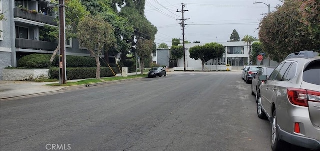 view of road with traffic signs, street lighting, curbs, and sidewalks