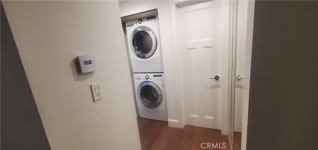 washroom featuring laundry area, stacked washer / dryer, and dark wood finished floors