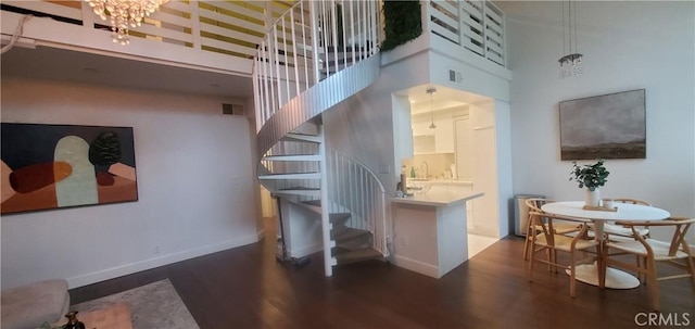 kitchen featuring baseboards, visible vents, a towering ceiling, dark wood-style floors, and a chandelier