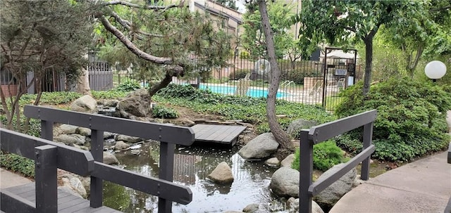 surrounding community with fence and a pool