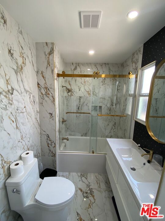 full bathroom featuring bath / shower combo with glass door, toilet, and vanity