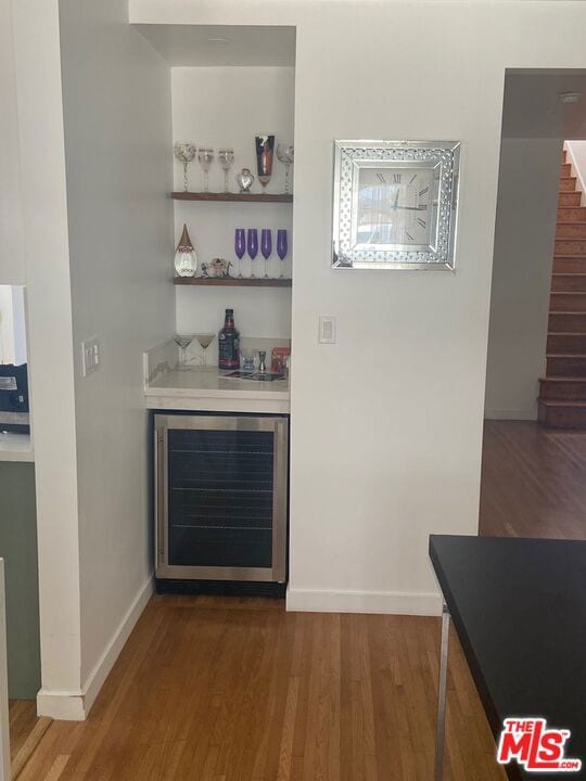 bar with wine cooler and hardwood / wood-style floors