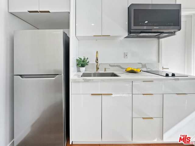 kitchen with sink, white cabinets, light stone counters, and stainless steel appliances