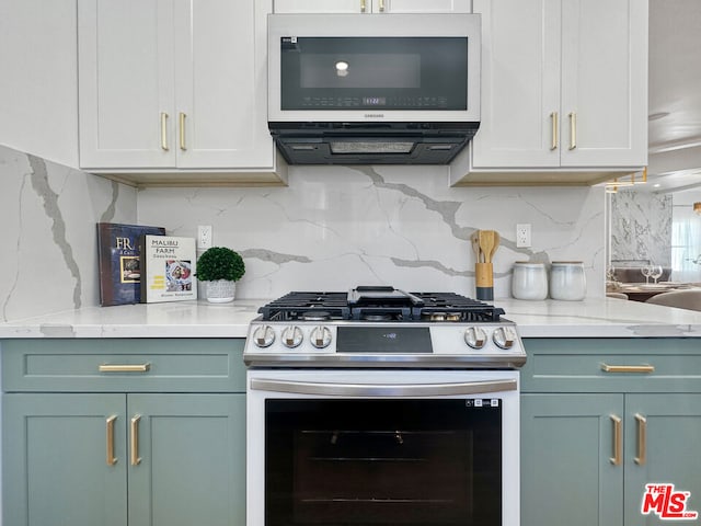 kitchen featuring white cabinetry, light stone counters, stainless steel appliances, and tasteful backsplash