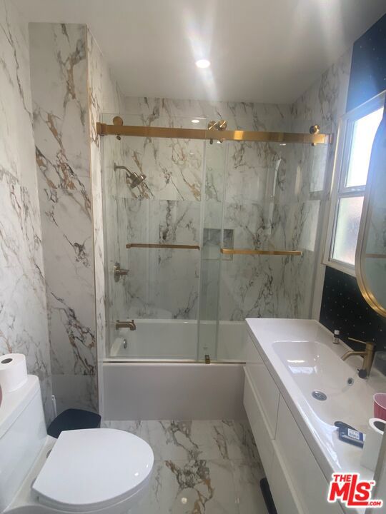 full bathroom featuring toilet, enclosed tub / shower combo, and vanity