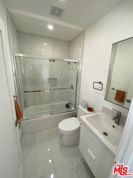 full bathroom with toilet, vanity, and shower / bath combination with glass door