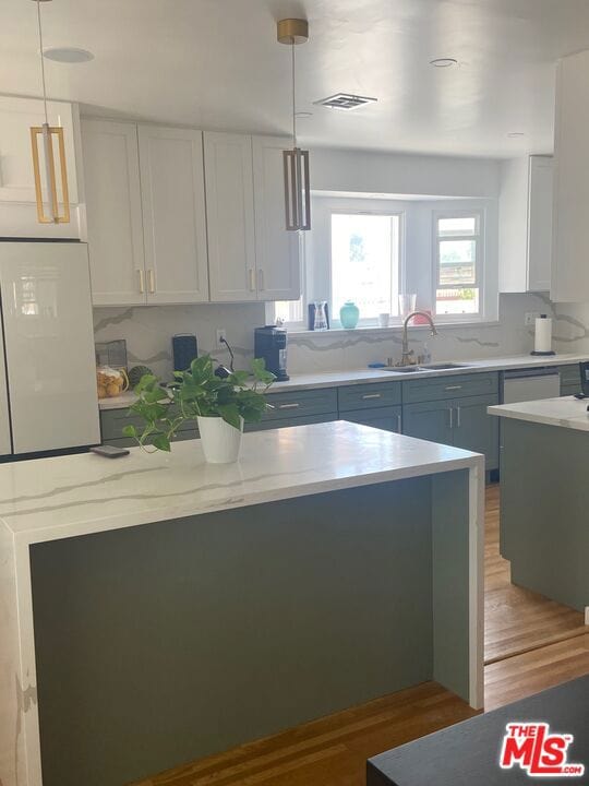 kitchen with white cabinets, sink, wood-type flooring, and pendant lighting