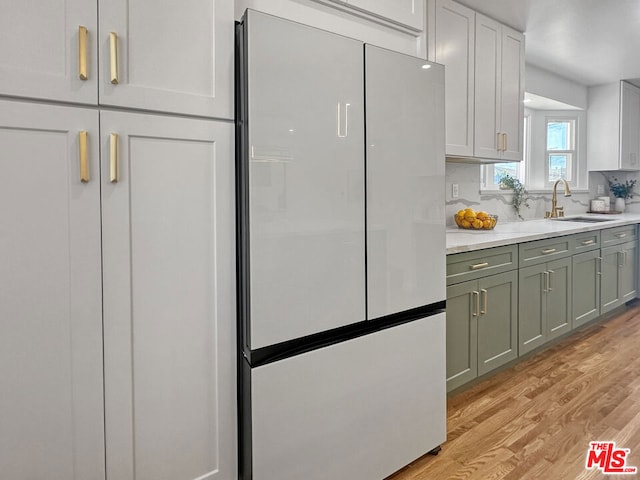 kitchen featuring sink, white fridge, light wood-type flooring, and tasteful backsplash