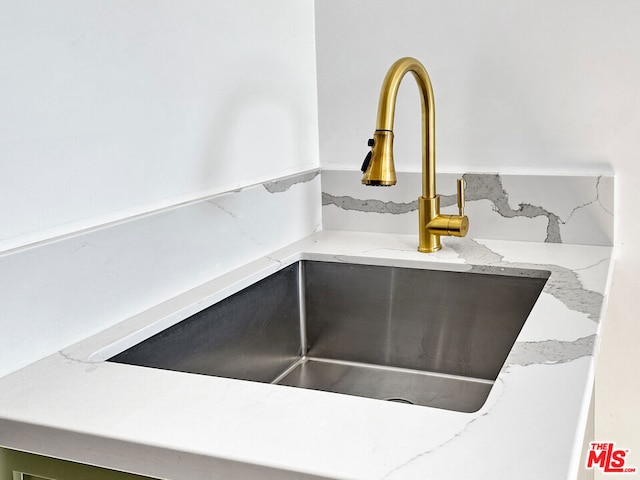 interior details featuring sink, light stone counters, and backsplash