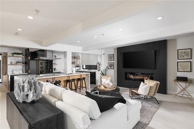 living room with a fireplace, beamed ceiling, and light wood-type flooring