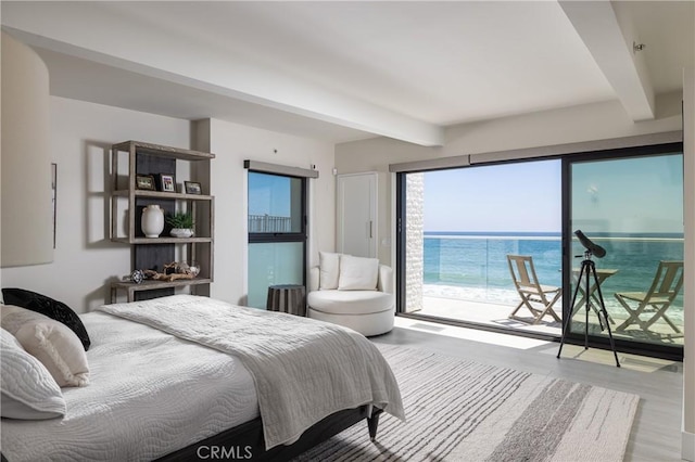 bedroom featuring beam ceiling, a water view, light hardwood / wood-style floors, and access to outside