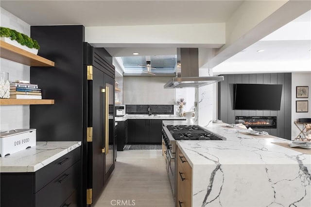 35651 Beach Rd, Dana Point, CA 92624 - kitchen with island range hood, range with two ovens, open shelves, dark cabinets, and a sink