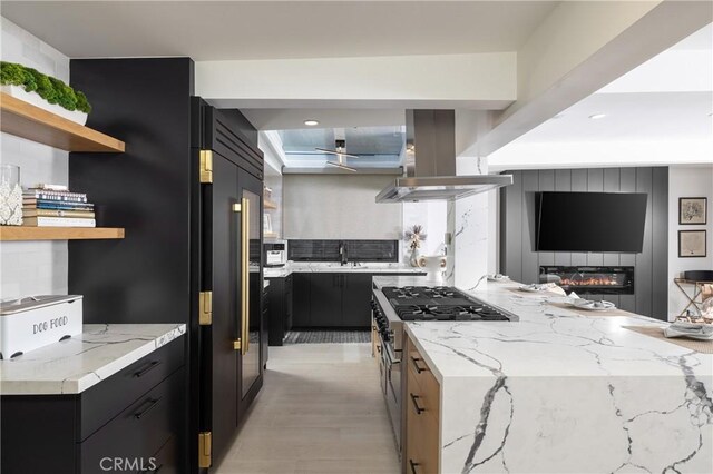 35651 Beach Rd, Dana Point, CA 92624 - kitchen with island range hood, high end stainless steel range, open shelves, dark cabinetry, and light stone counters