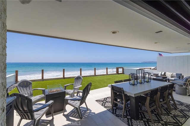 view of patio featuring a beach view, a water view, and an outdoor fire pit